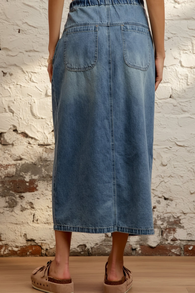 Person wearing a blue denim skirt against a pink background
