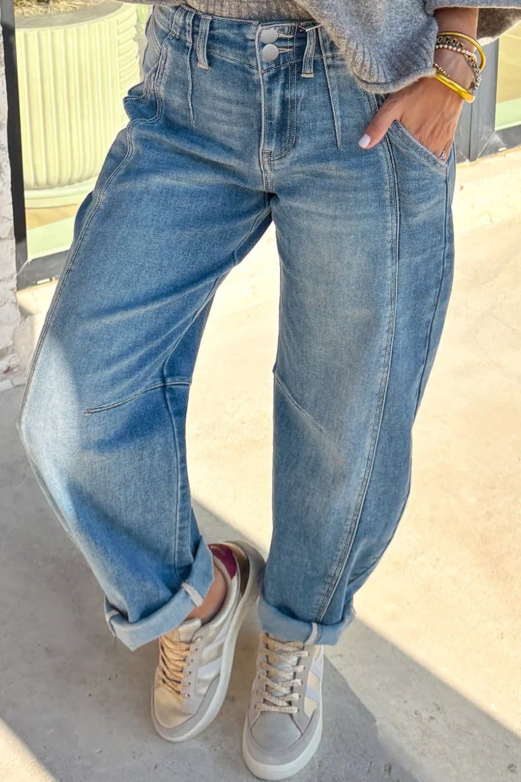 Person wearing blue jeans and white sneakers on a light background