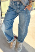 Person wearing blue jeans and white sneakers on a light background
