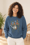 The Doodled Flower Boutique indigo blue crewneck sweatshirt featuring an original floral watering can graphic, close up.