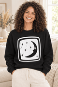The Doodled Flower Boutique black crewneck sweatshirt featuring an original crescent moon and stars graphic, close up.