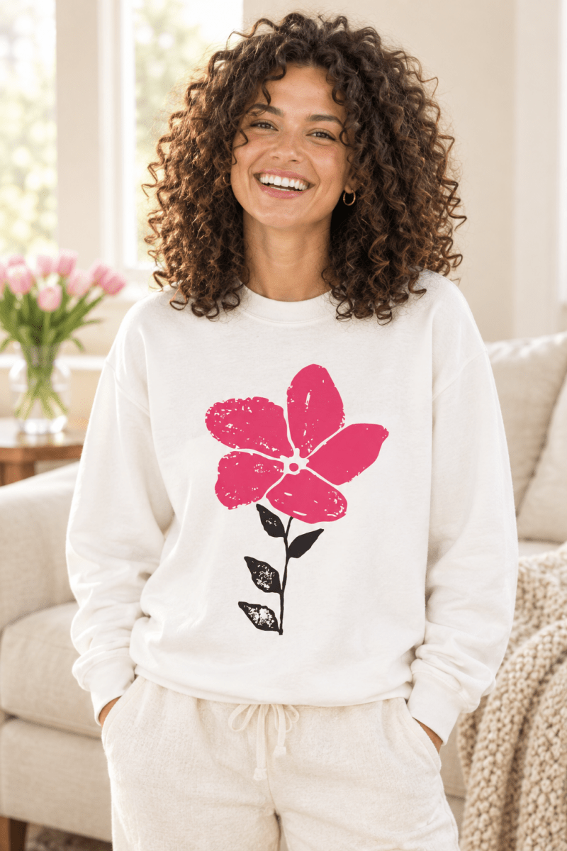 The Doodled Flower Boutique white crewneck sweatshirt featuring an original pink bloom doodle graphic, close up.