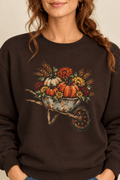 The Doodled Flower Boutique dark chocolate crewneck sweatshirt featuring a rustic autumn wheelbarrow of pumpkins and mums graphic, close up