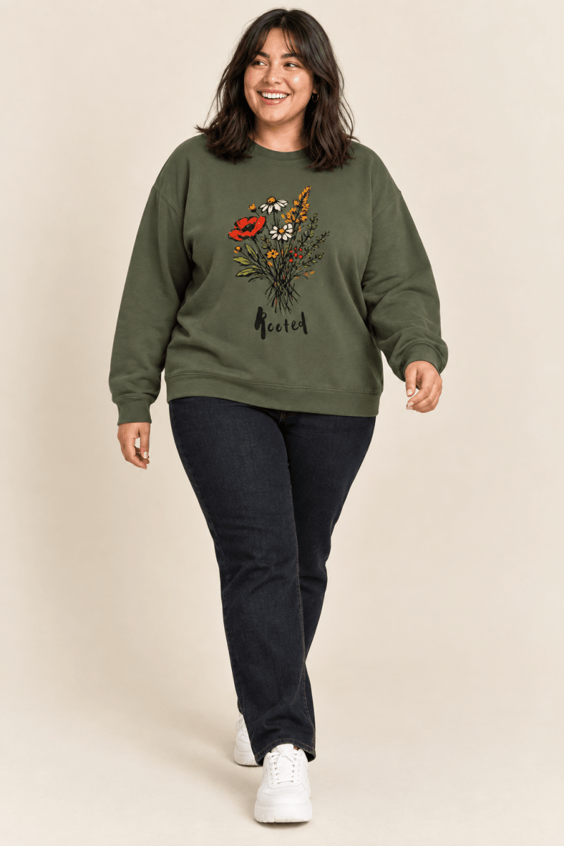 The Doodled Flower Boutique military green rooted floral crewneck sweatshirt worn by a model with dark wash jeans and white sneakers.