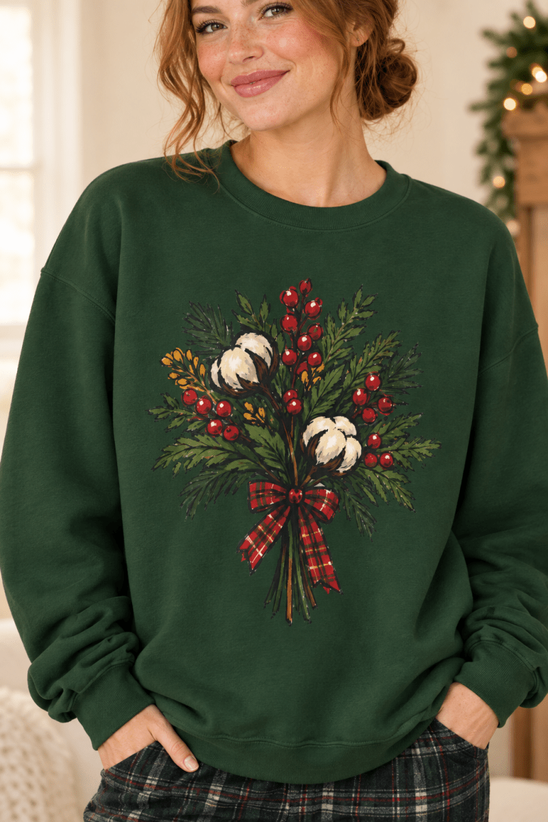 The Doodled Flower Boutique forest green crewneck sweatshirt featuring a cotton bouquet with red berries and a plaid bow graphic, close up.