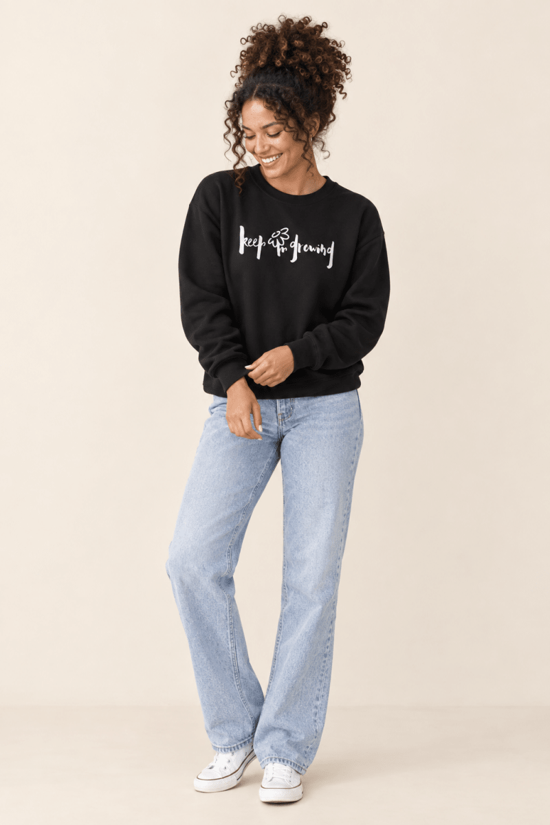 The Doodled Flower Boutique black keep growing crewneck sweatshirt styled with light wash straight jeans and white sneakers.