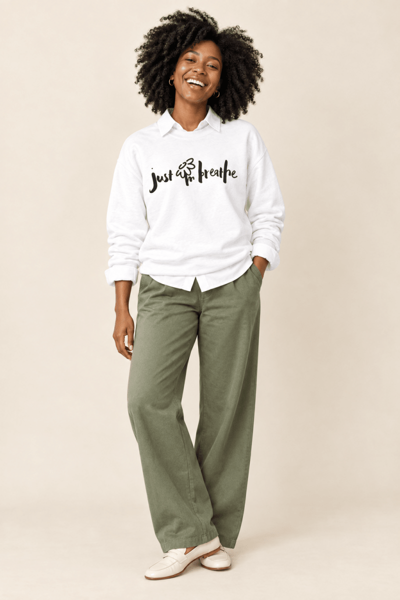 The Doodled Flower Boutique white just breathe crewneck sweatshirt layered over a white button-down with olive wide leg trousers and loafers.