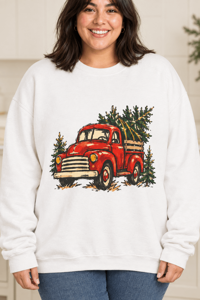 The Doodled Flower Boutique white crewneck sweatshirt featuring a textless vintage red Christmas truck carrying an evergreen tree graphic, close up.