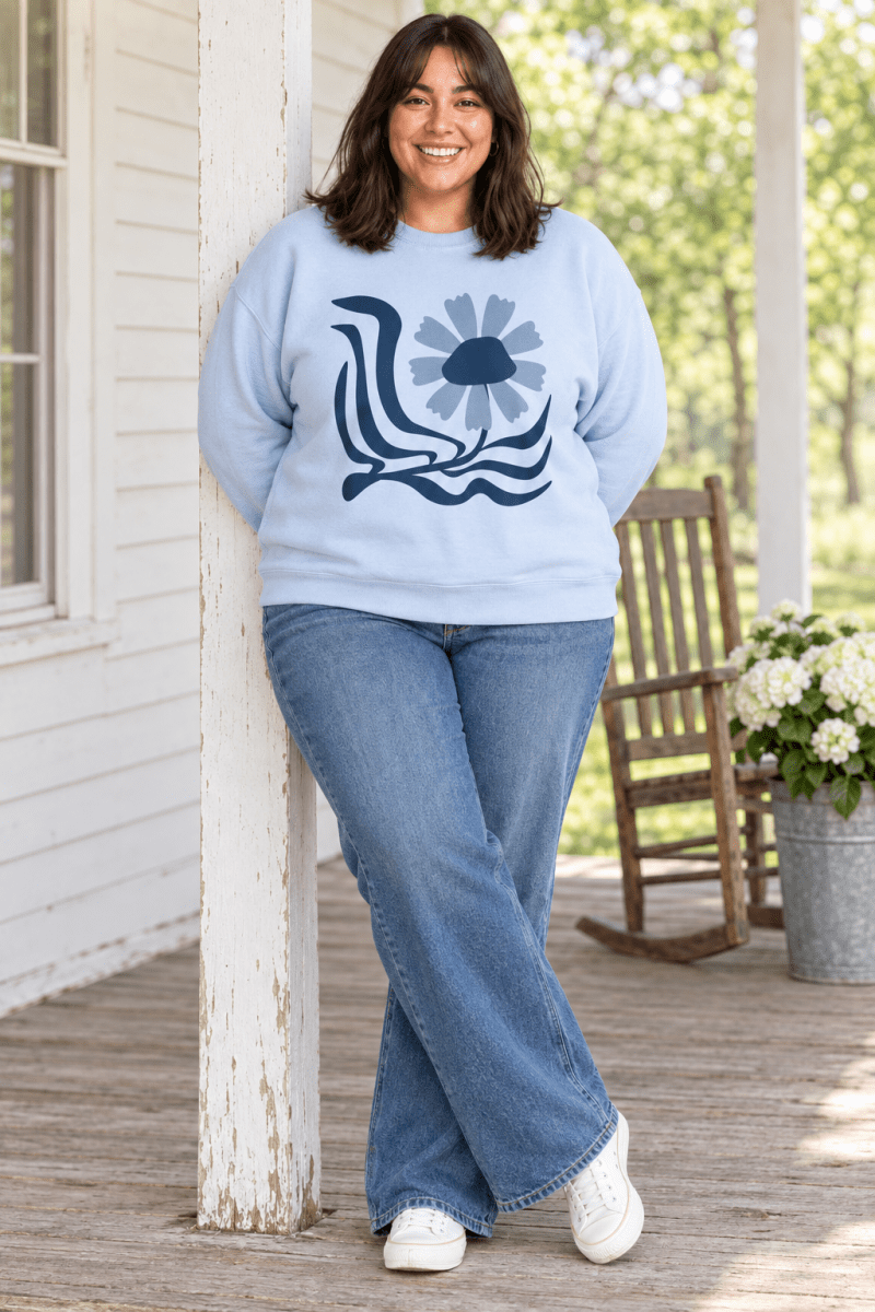 The Doodled Flower Boutique light blue retro floral wave crewneck sweatshirt styled with wide leg jeans and white sneakers on a farmhouse porch.