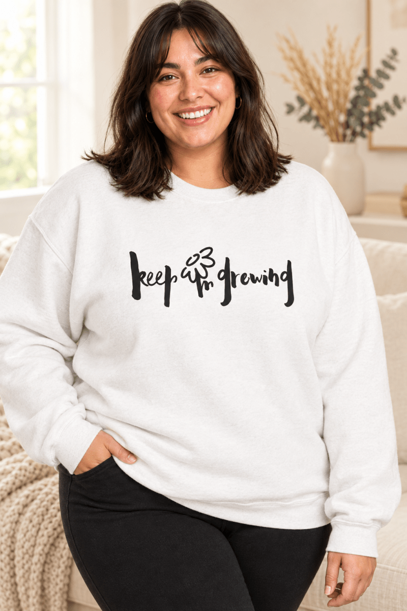 The Doodled Flower Boutique white crewneck sweatshirt featuring an original hand-lettered keep growing graphic with a doodled daisy, close up.