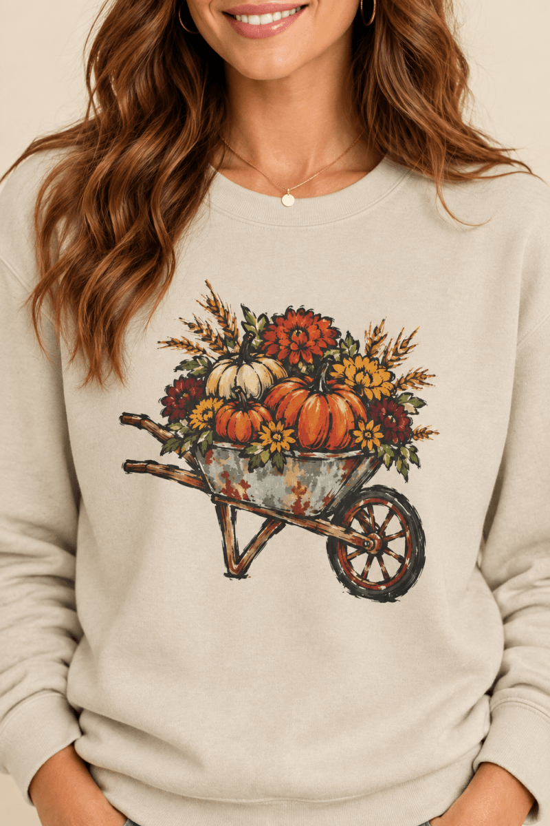 The Doodled Flower Boutique sand crewneck sweatshirt featuring a rustic autumn wheelbarrow of pumpkins and mums graphic, close up
