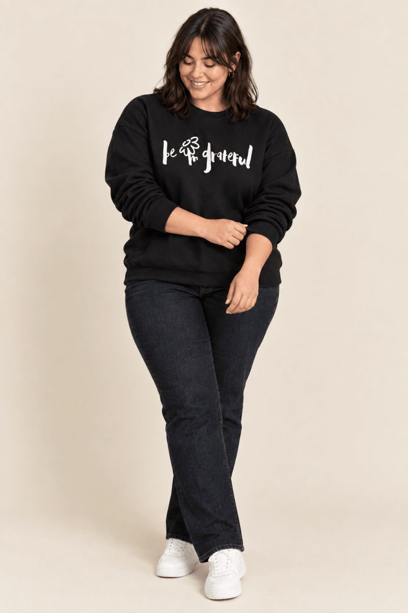 The Doodled Flower Boutique black be grateful crewneck sweatshirt styled with dark wash straight jeans and white sneakers.