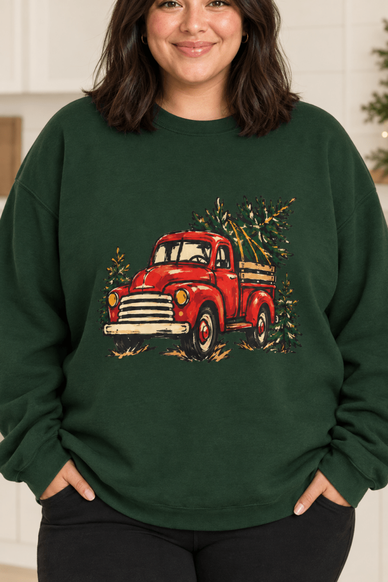 The Doodled Flower Boutique forest green crewneck sweatshirt featuring a textless vintage red Christmas truck carrying an evergreen tree graphic, close up.