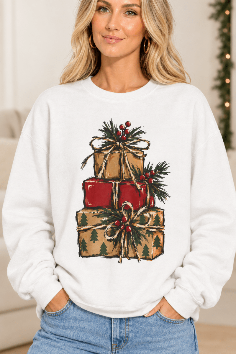 The Doodled Flower Boutique white crewneck sweatshirt featuring a stacked presents graphic with evergreen sprigs and red berries, close up.