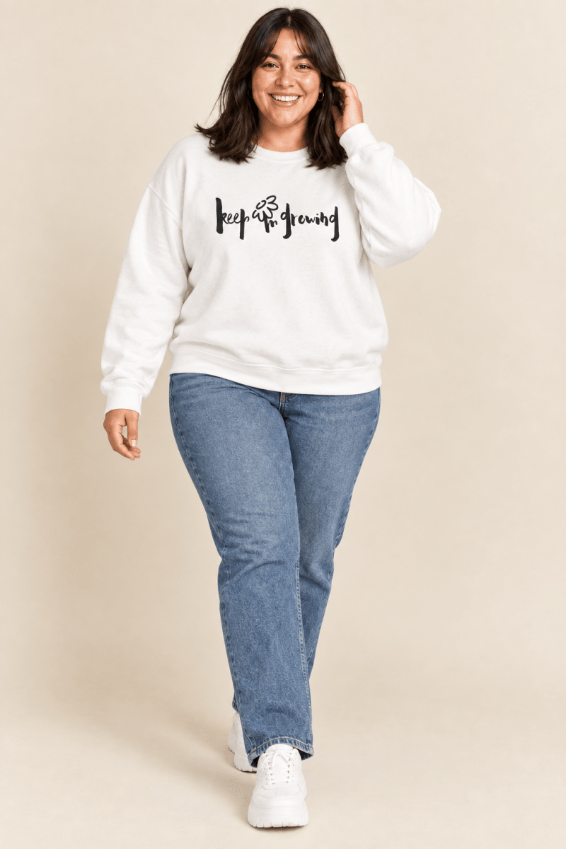 The Doodled Flower Boutique white keep growing crewneck sweatshirt worn by a model with straight leg jeans and white sneakers.