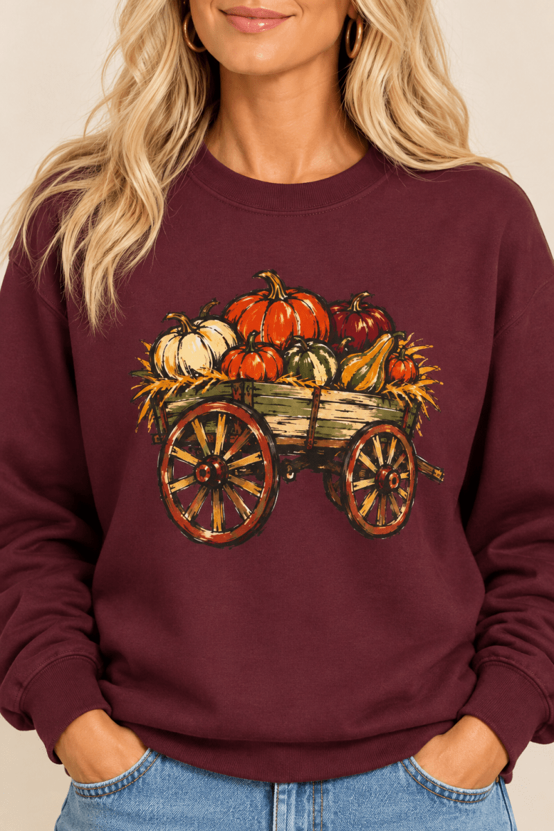 The Doodled Flower Boutique maroon crewneck sweatshirt featuring a rustic pumpkin wagon graphic, close up