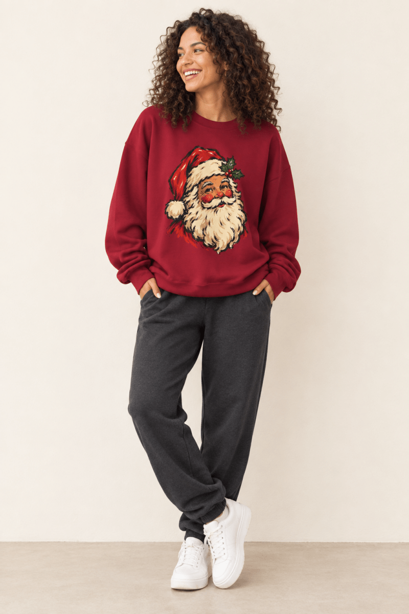 The Doodled Flower Boutique cardinal red crewneck sweatshirt featuring a vintage Santa portrait with a holly sprig graphic, worn by a model.