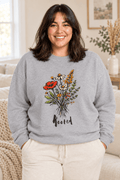 The Doodled Flower Boutique sport grey crewneck sweatshirt featuring an original rooted wildflower bouquet graphic, close up.