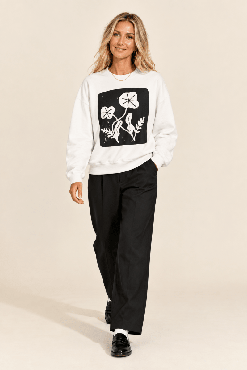 The Doodled Flower Boutique white floral block print crewneck sweatshirt worn by a model with black wide leg trousers and patent loafers.