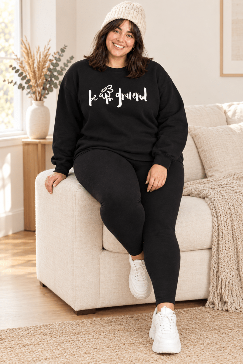 The Doodled Flower Boutique black be grateful crewneck sweatshirt styled with black leggings, white sneakers and a cream beanie.