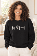 The Doodled Flower Boutique black crewneck sweatshirt featuring an original hand-lettered keep growing graphic with a doodled daisy, close up.
