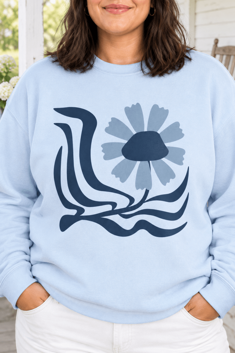The Doodled Flower Boutique light blue crewneck sweatshirt featuring an original retro floral wave graphic, close up.
