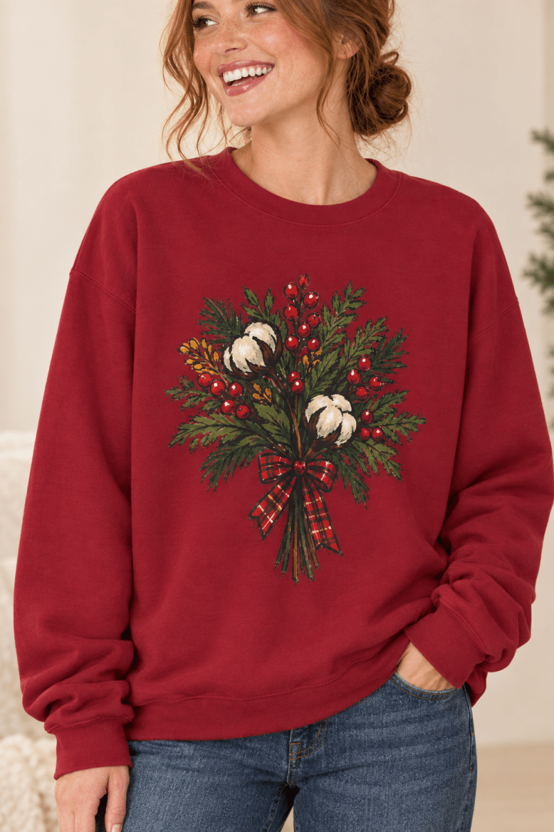 The Doodled Flower Boutique cardinal red crewneck sweatshirt featuring a cotton bouquet with red berries and a plaid bow graphic, close up.