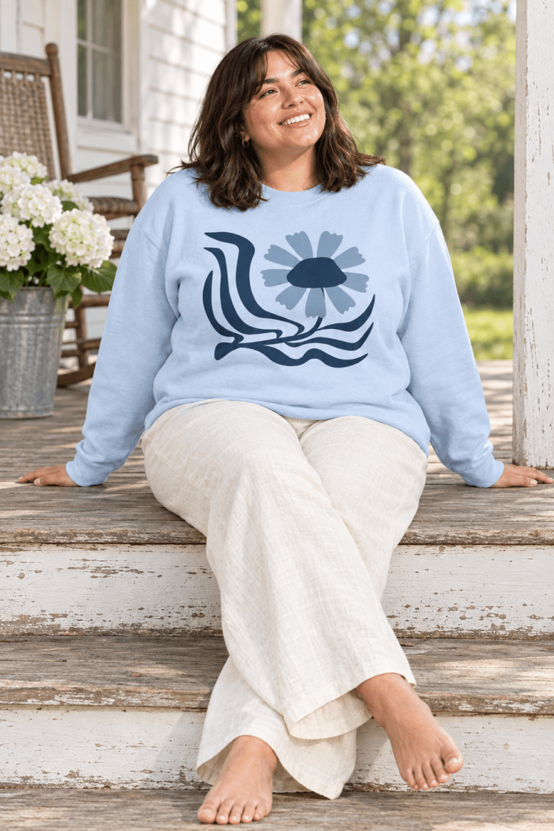 The Doodled Flower Boutique light blue retro floral wave crewneck sweatshirt styled with cream linen trousers on farmhouse porch steps.