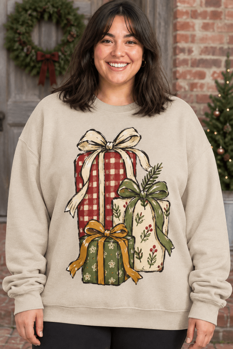 Woman wearing The Doodled Flower Boutique cream fleece sweatshirt with hand-drawn Christmas gift stack illustration.