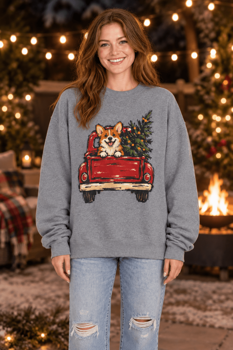 Woman wearing The Doodled Flower Boutique grey sweatshirt with a corgi in a red vintage truck Christmas graphic