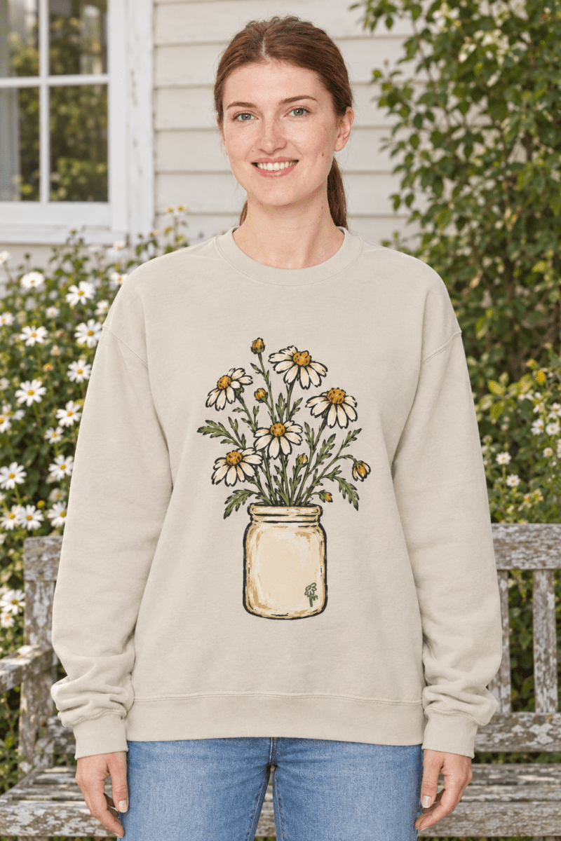 Woman wearing The Doodled Flower Boutique cream fleece crewneck sweatshirt with hand-drawn daisy bouquet illustration.
