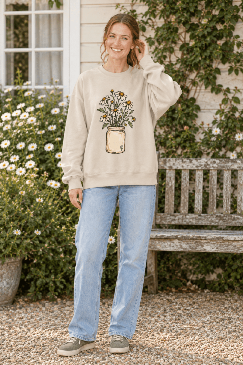 The Doodled Flower Boutique cream crewneck sweatshirt with a hand-drawn daisy bouquet print worn by a smiling woman.