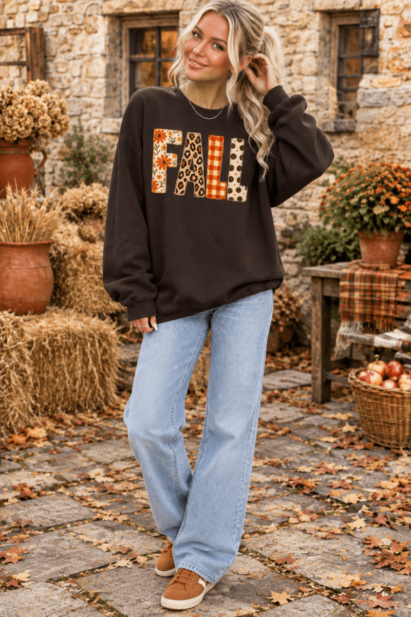 The Doodled Flower Boutique dark chocolate crewneck sweatshirt with mixed-print FALL lettering worn by a blonde woman.