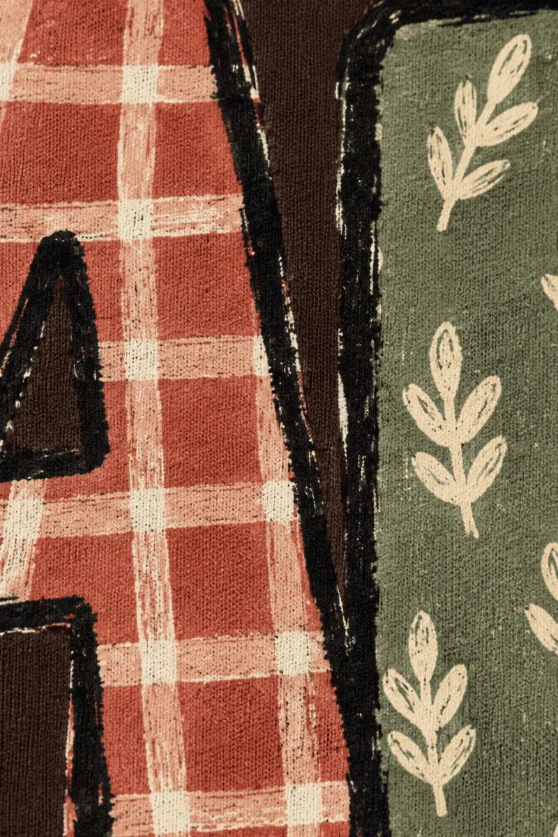 Close-up of The Doodled Flower Boutique espresso sweatshirt featuring FALL lettering with gingham and leaf patterns.