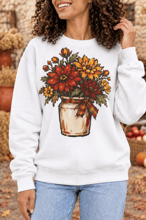 Woman wearing a The Doodled Flower Boutique white crewneck sweatshirt with a hand-drawn fall mum floral graphic.