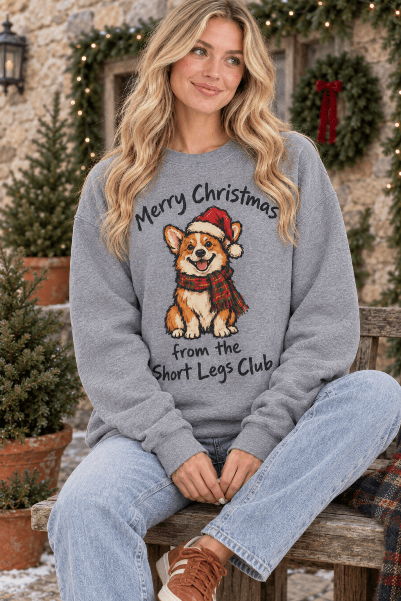 The Doodled Flower Boutique graphite heather crewneck sweatshirt with a festive corgi graphic on a woman outdoors.