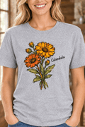 The Doodled Flower Boutique grey cotton t-shirt featuring a hand-drawn orange and ochre calendula flower illustration.