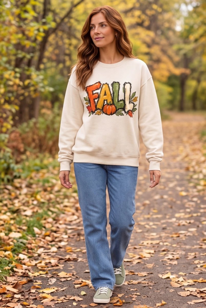 The Doodled Flower Boutique ivory cotton crewneck sweatshirt with autumn leaf and pumpkin graphic worn in a park.