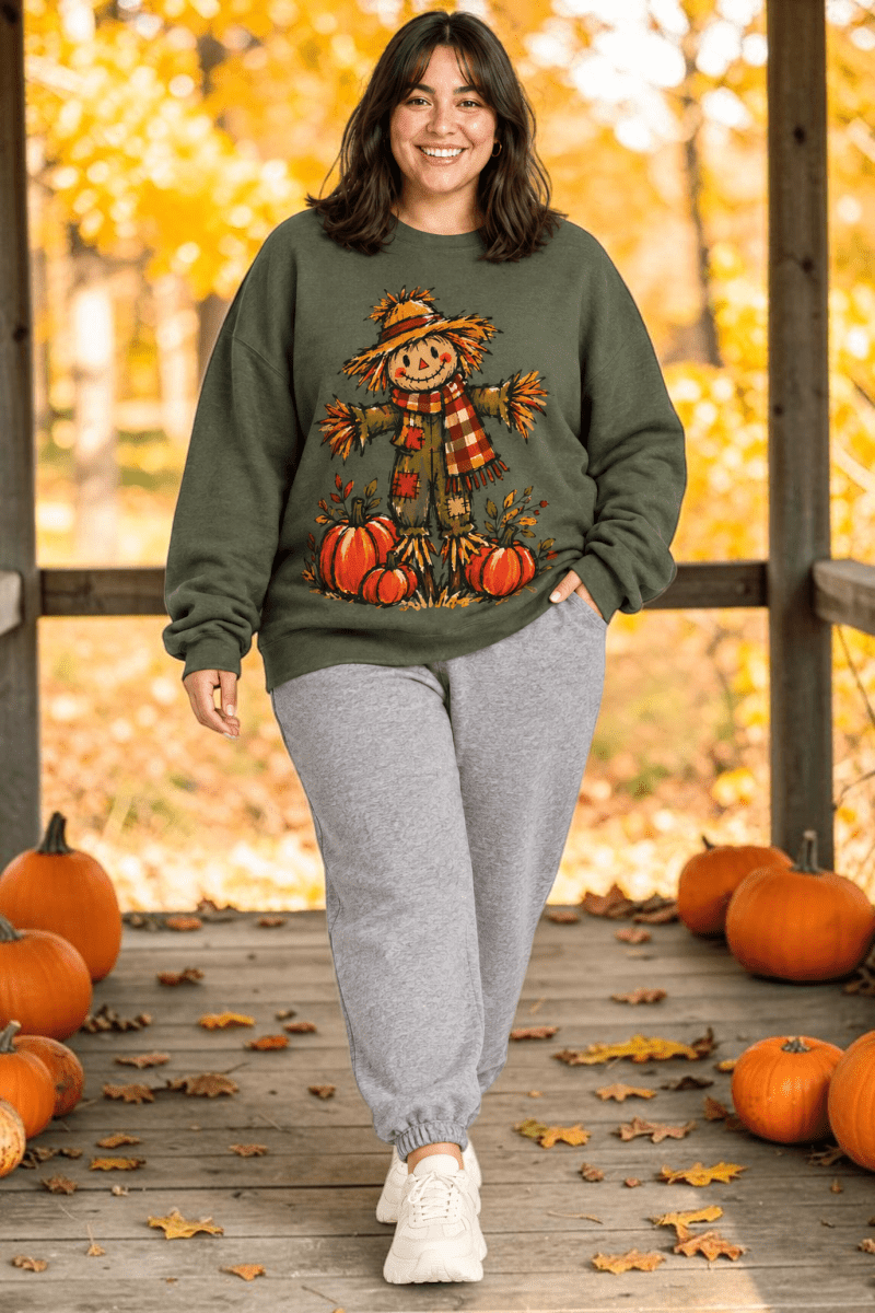 The Doodled Flower Boutique olive green crewneck sweatshirt featuring a hand-drawn scarecrow and pumpkin harvest print.