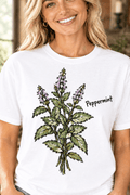 The Doodled Flower Boutique white cotton t-shirt featuring a hand-drawn green and purple peppermint botanical graphic.