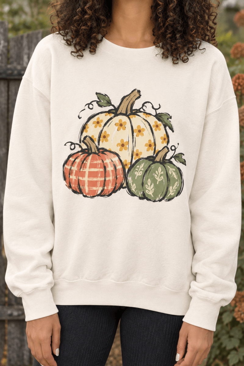 The Doodled Flower Boutique ivory crewneck sweatshirt featuring a hand-drawn floral pumpkin trio print for autumn.