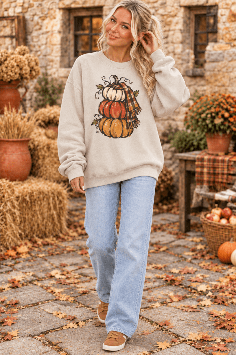 The Doodled Flower Boutique cream crewneck sweatshirt featuring a hand-drawn stacked pumpkin and plaid scarf design.