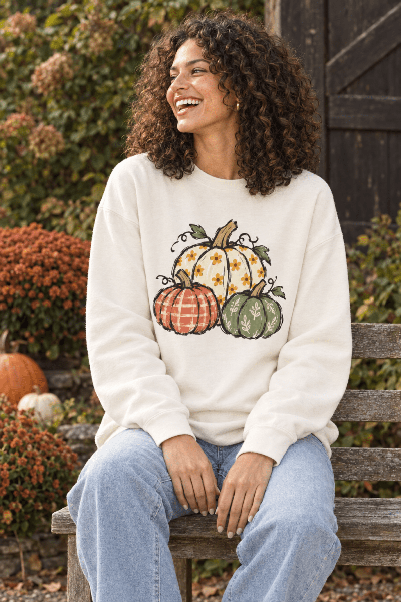 Woman wearing The Doodled Flower Boutique ivory crewneck sweatshirt with a hand-drawn floral pumpkin trio design.