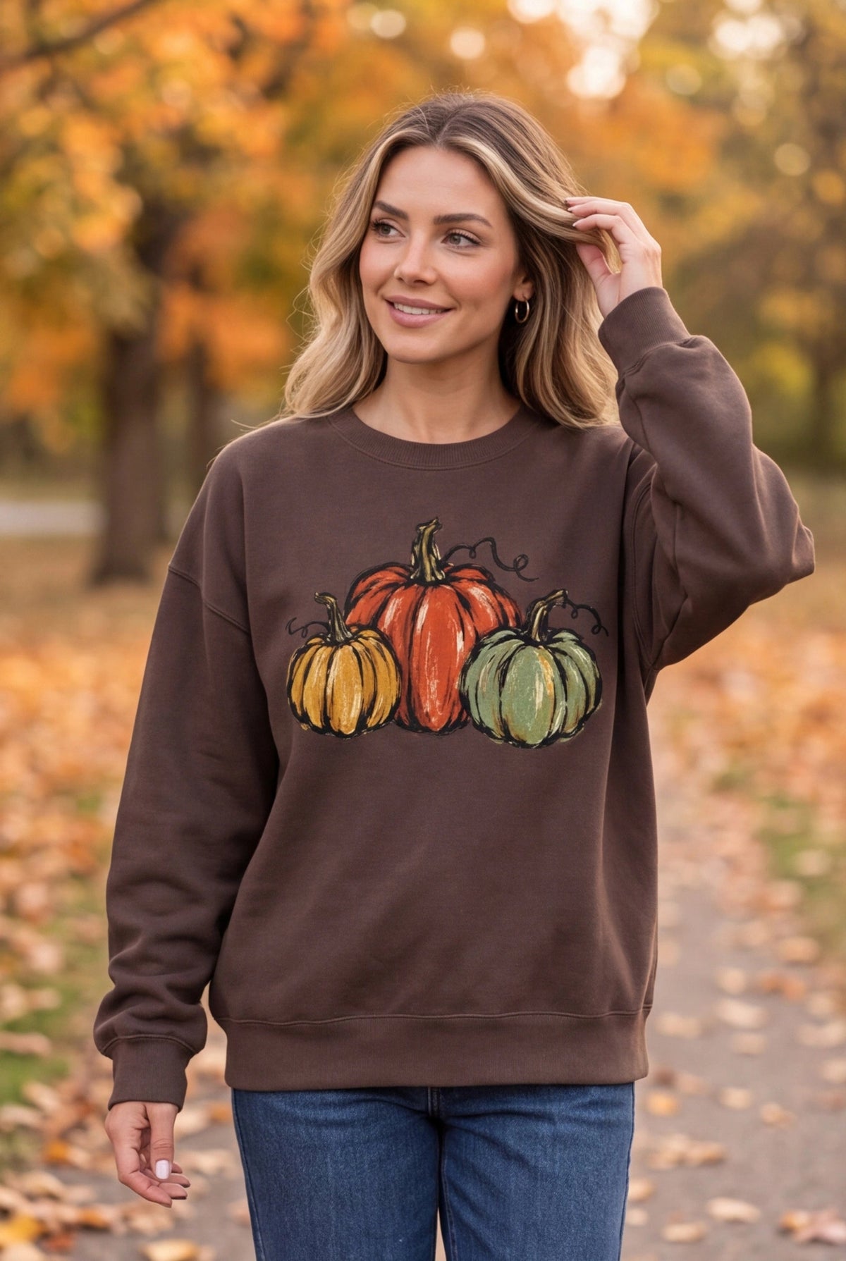 Woman wearing The Doodled Flower Boutique espresso brown cotton sweatshirt with watercolor pumpkin illustration