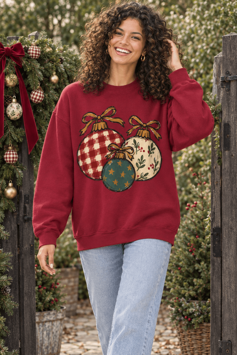The Doodled Flower Boutique red crewneck sweatshirt featuring a hand-drawn Christmas ornament trio in plaid and floral
