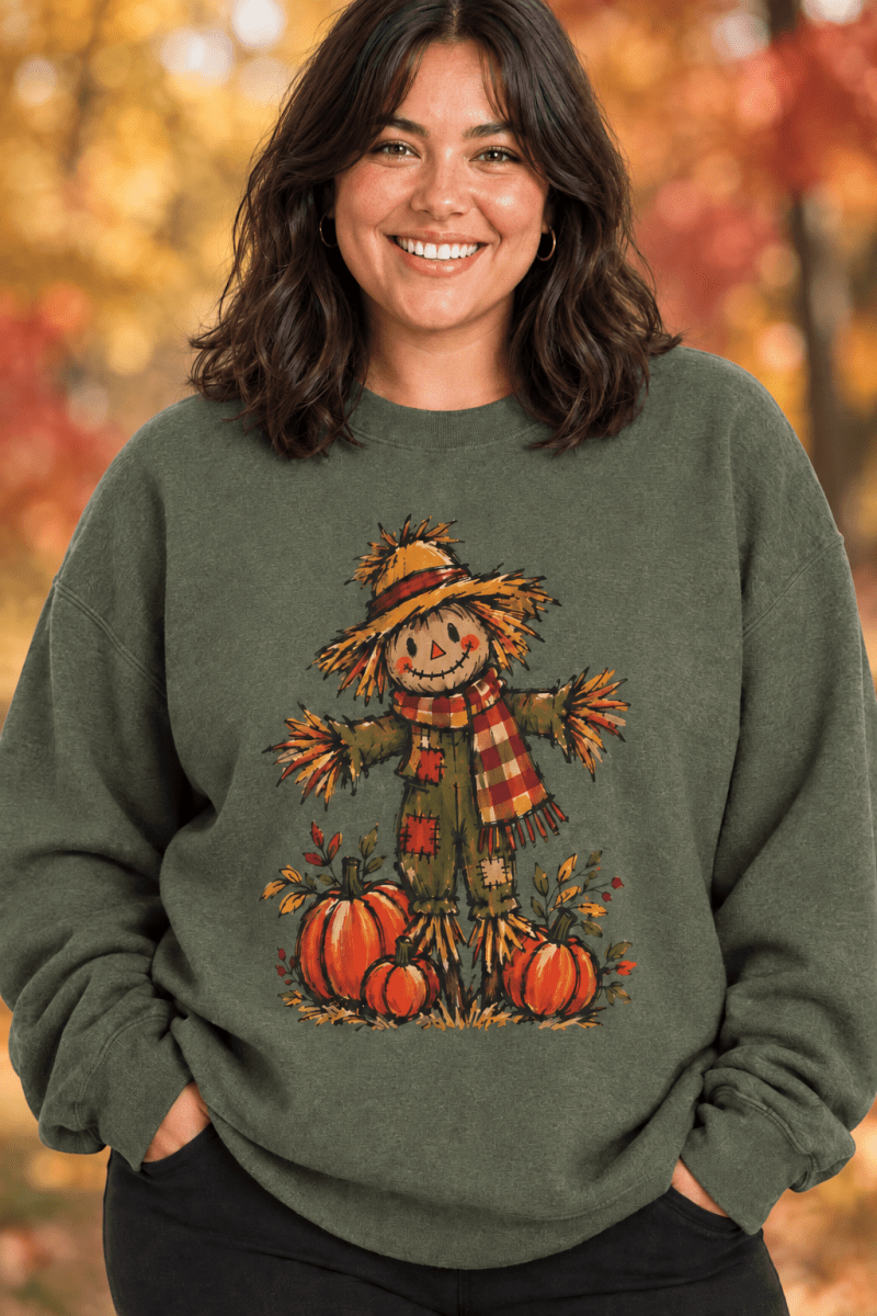 The Doodled Flower Boutique olive green crewneck sweatshirt featuring a hand-drawn scarecrow and pumpkin patch design.