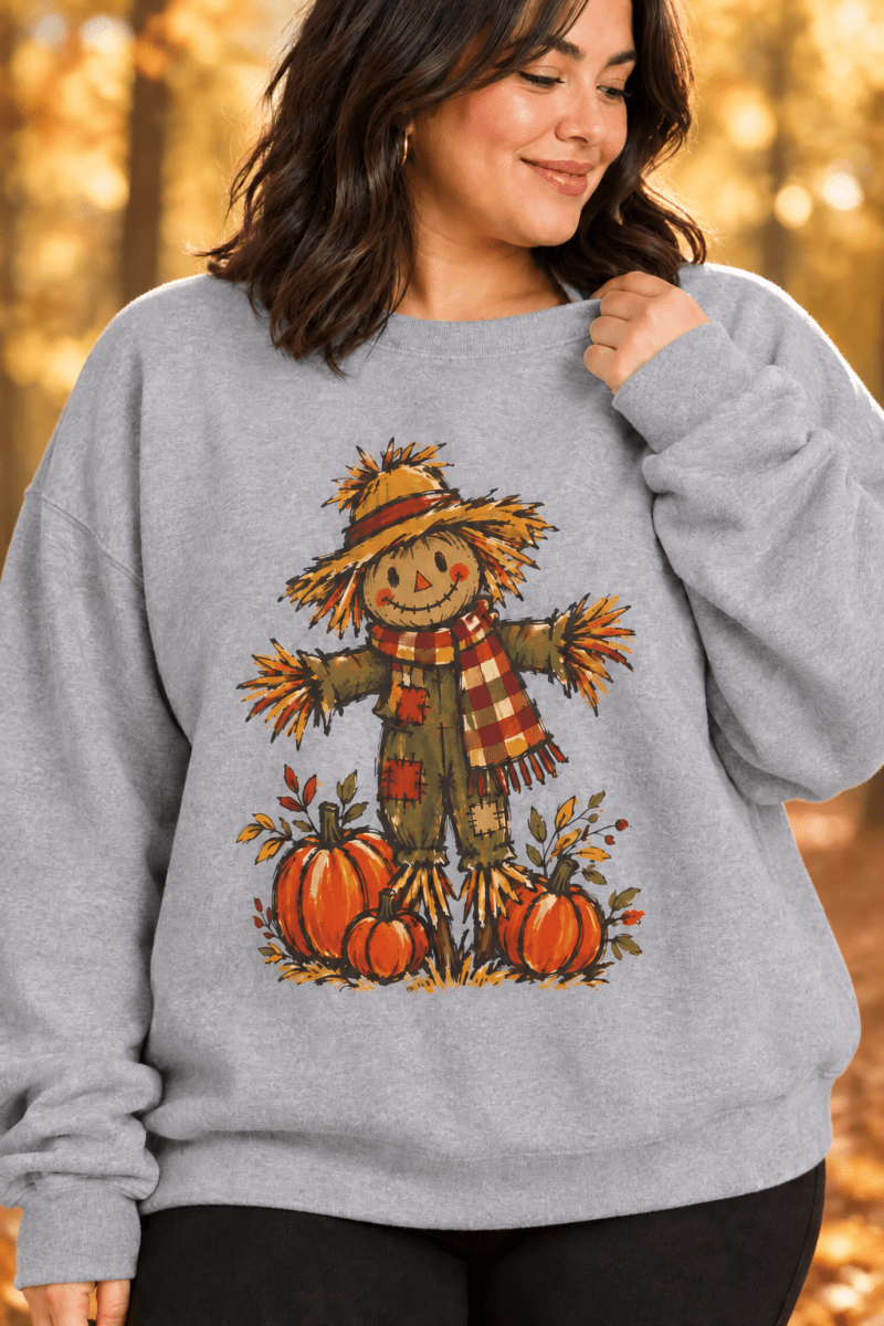 The Doodled Flower Boutique grey crewneck sweatshirt featuring a hand-drawn scarecrow and pumpkin harvest graphic.