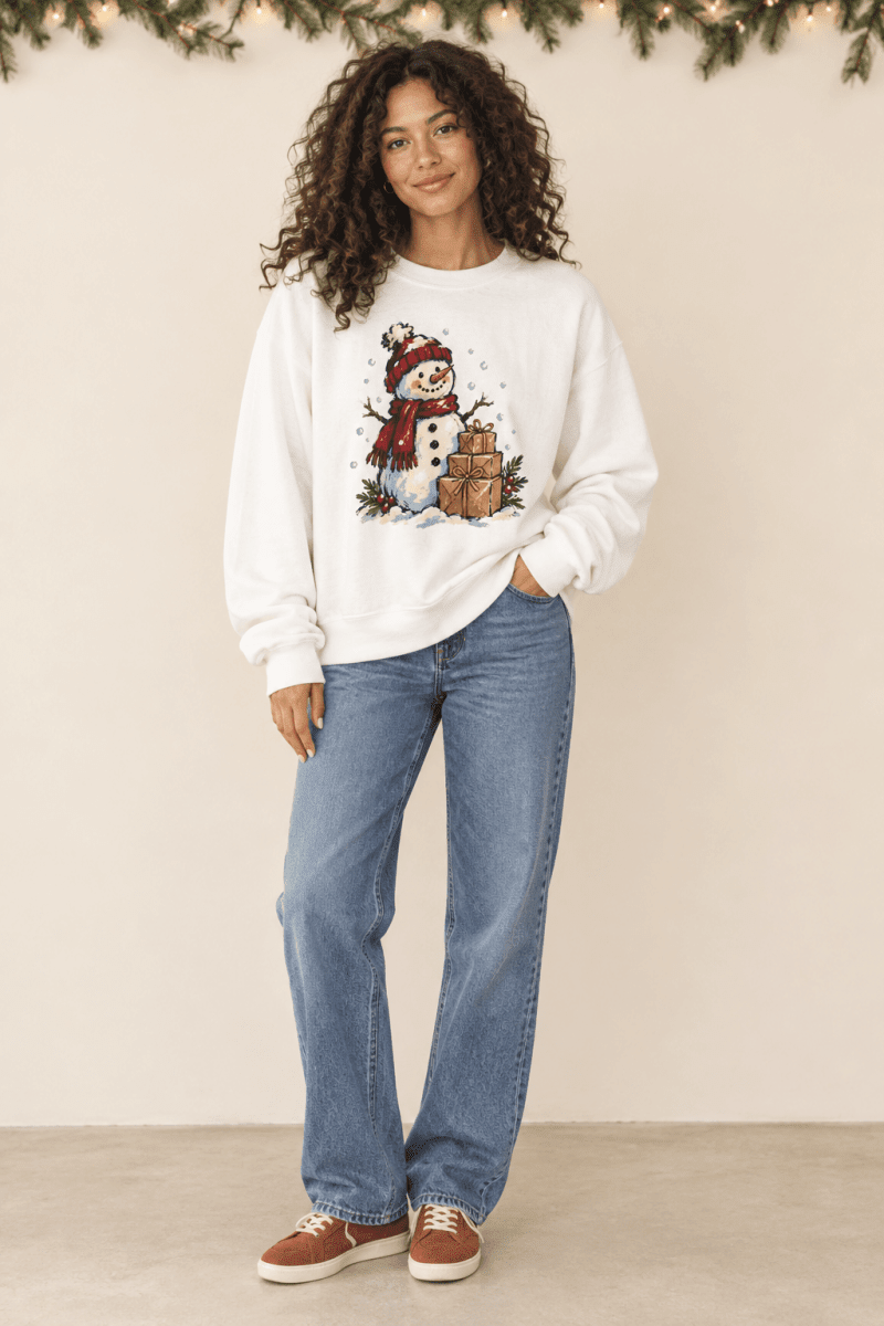 The Doodled Flower Boutique white crewneck sweatshirt featuring a hand-drawn snowman and gifts graphic on a model.